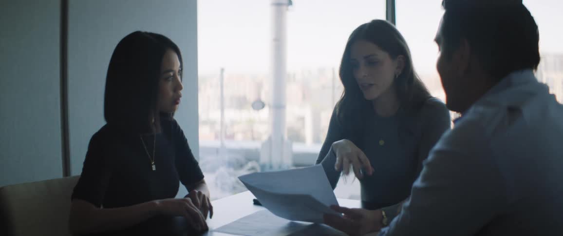 Three people sitting at an office table talking