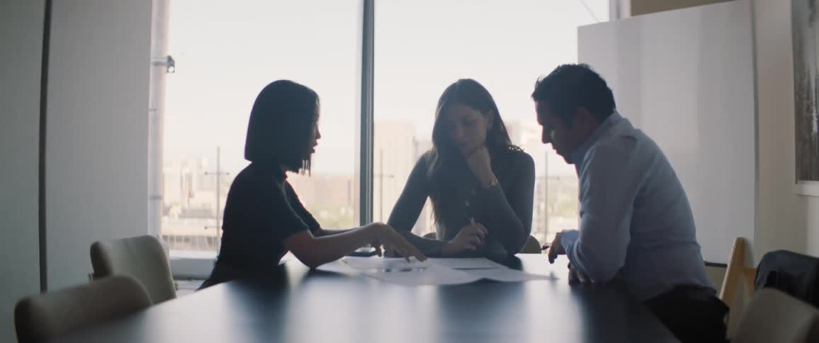 Three people have a meeting in a conference room