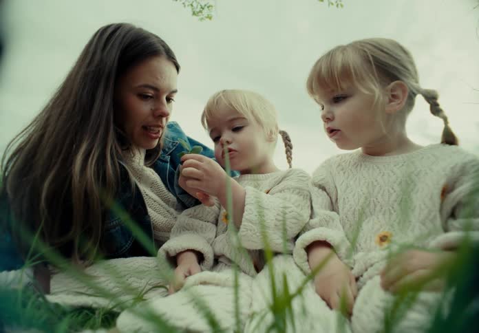 Mother with her two little twin daughters in a garden