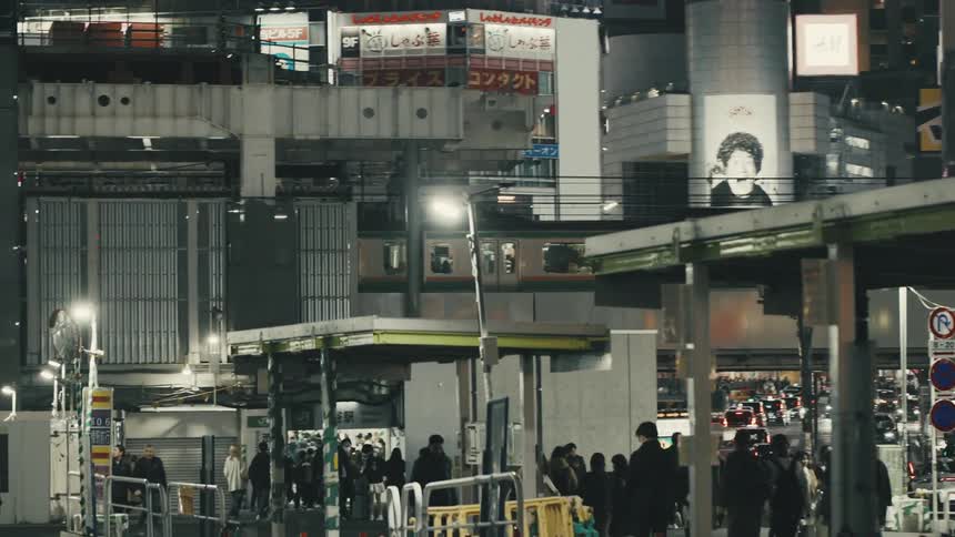 Dynamic dolly shot of the iconic Tokyo subway passing through a busy urban night scene near Shibuya