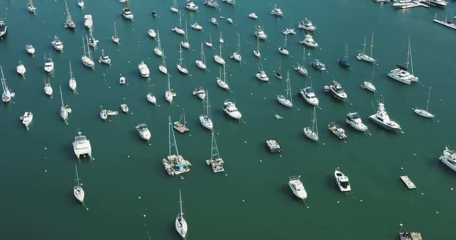 Various boats and floating platforms in a marina on a coast
