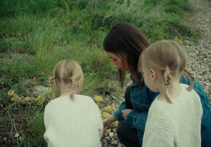 Mother with her two little daughters in a yellow flowerbed