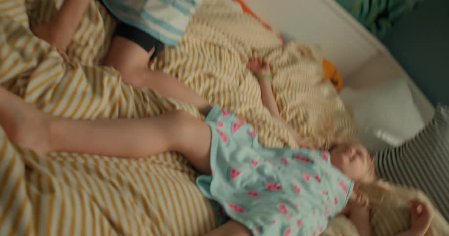 Siblings play on the bed