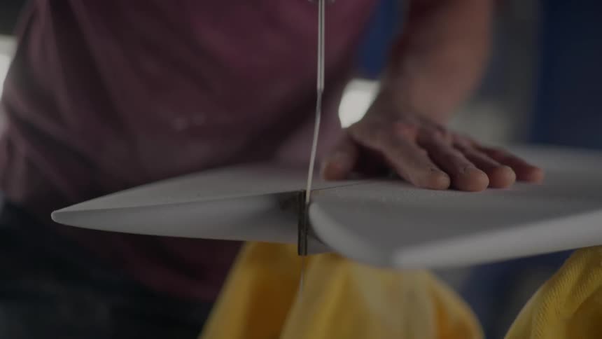 A man saws through two pieces of white wood