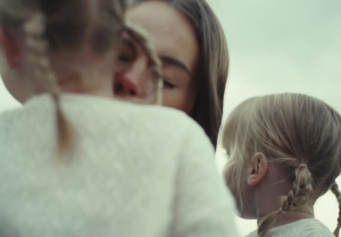 Mother sitting with her two twin daughters giving one of them a kiss