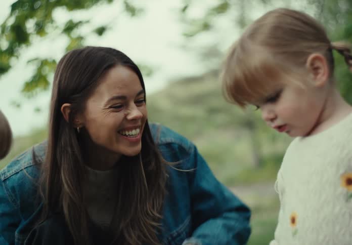Mother tickles one daughter while her other daughter looks on