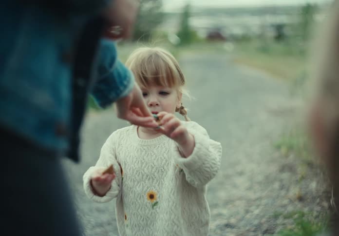 A mother gives her daughter treats while theyre standing on a path in nature
