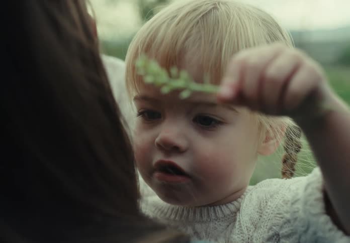 A womans daughter brushes her hair with a long piece of a plant