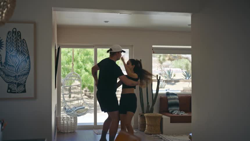 A couple is dancing making a spinning movement in a living room