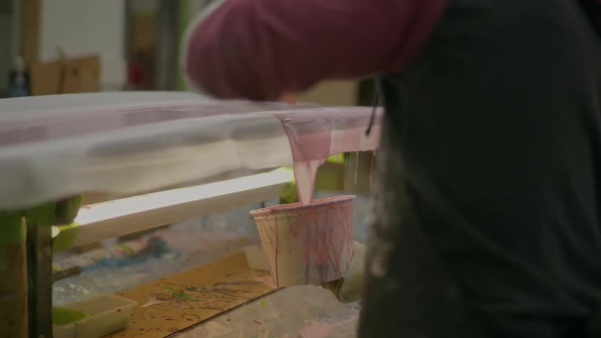 Person pouring liquid on a surfboard