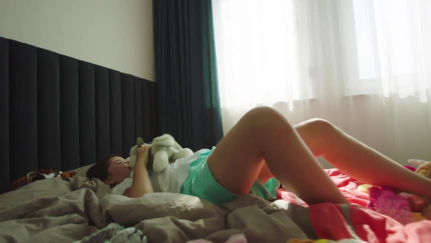 Girl jumping on the bed and playing with the teddy bear