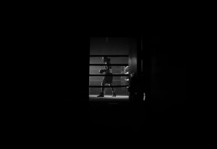 A boxer is standing in the ring under flashing lights