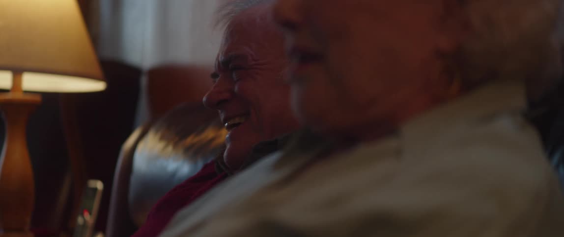 Elderly couple sitting on the sofa talking smiling