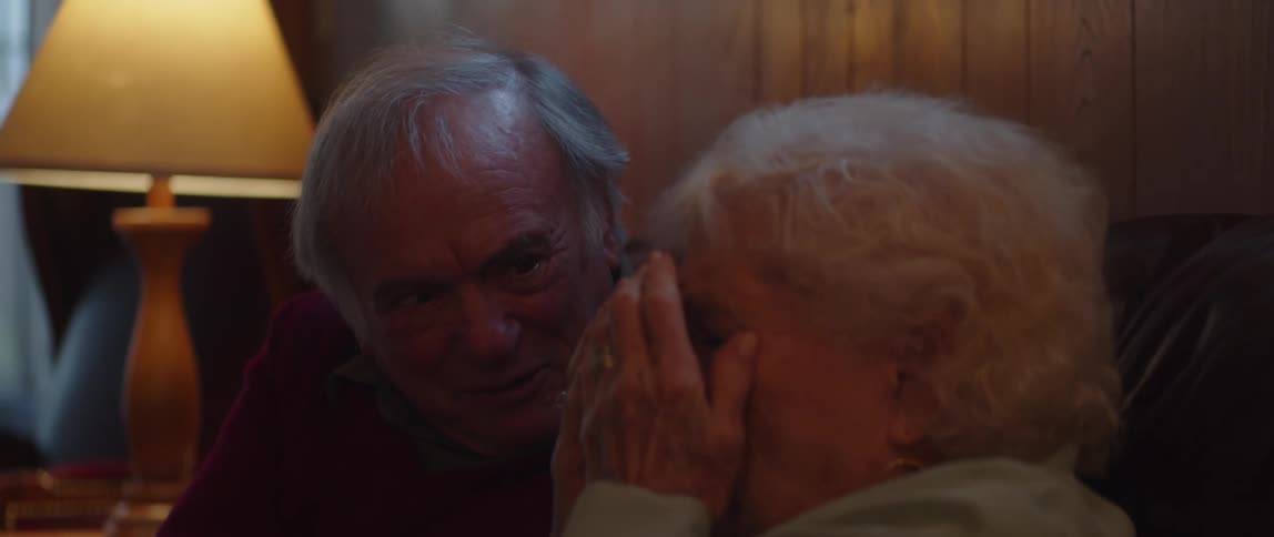 An elderly couple is spooked by what they are watching on tv