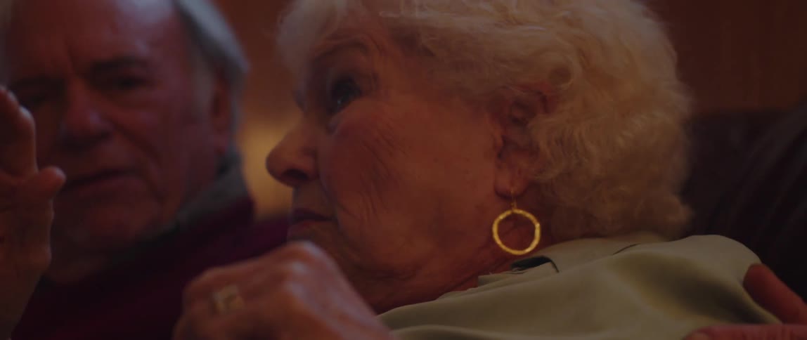 An elderly couple gets scared from something they see in a living room