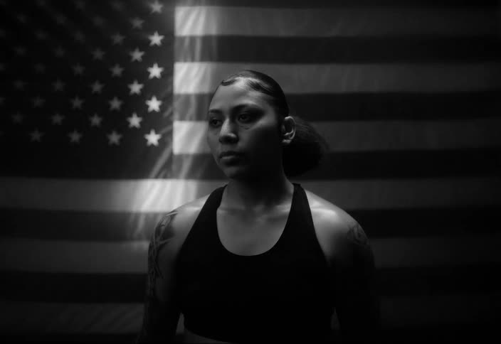 Portrait of a boxer woman with tattoos on her arms with the united states flag in the background