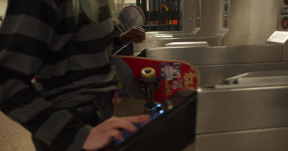 Two girls with skateboards pay to enter a subway