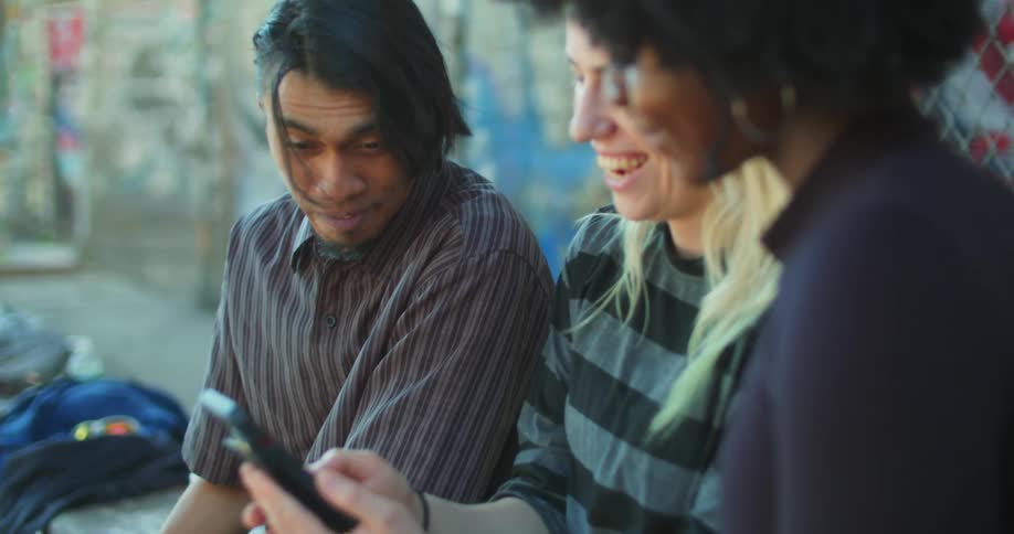 Three friends sitting with one of them in the middle using a cell phone