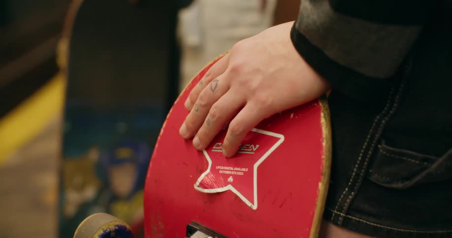 A close up of a hand resting on a red skateboard deck