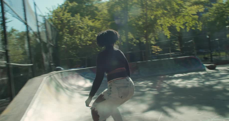Black skater girl skateboarding around a city skate park