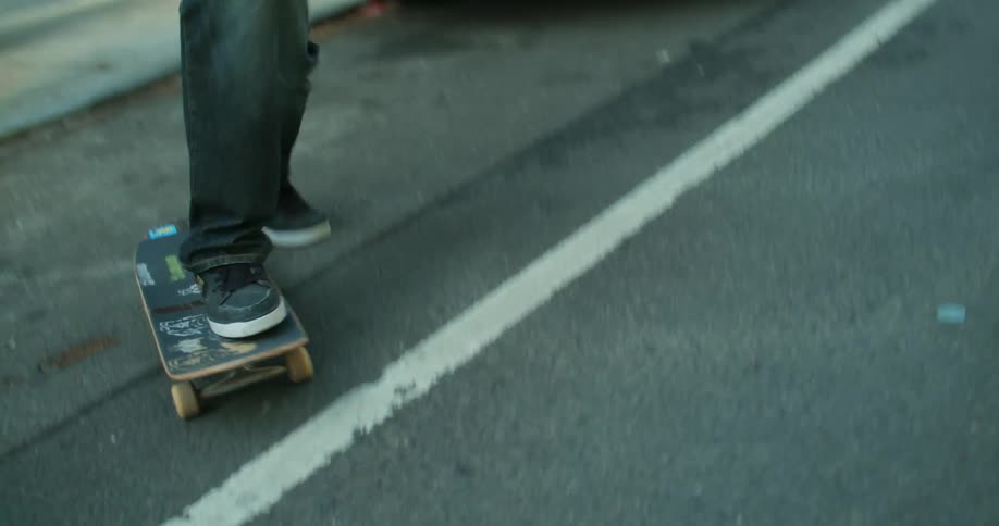 A young man rides a skateboard on the city street on a sunny day