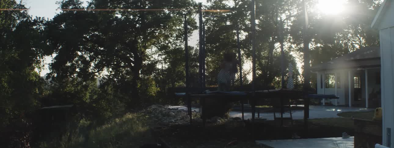 Kids jumping on a trampoline outside in the backyard