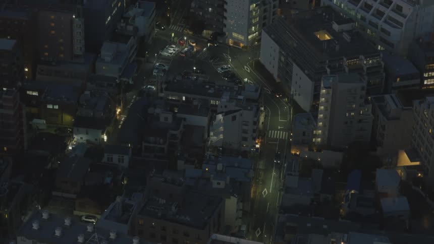 Cars drive on a road running through a city suburban area at night