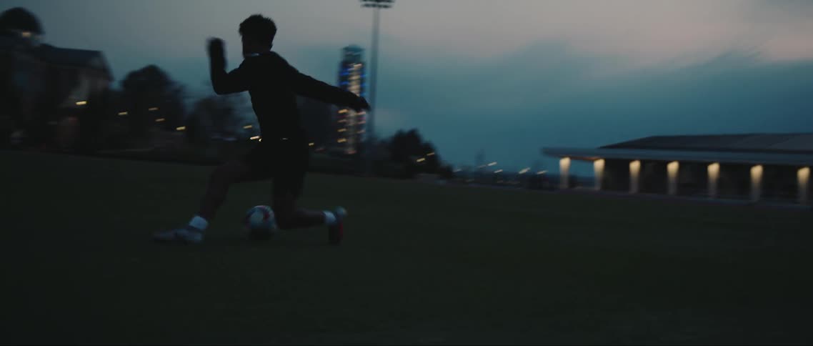 A young boy is kicking a soccer ball around the field performing maneuvers