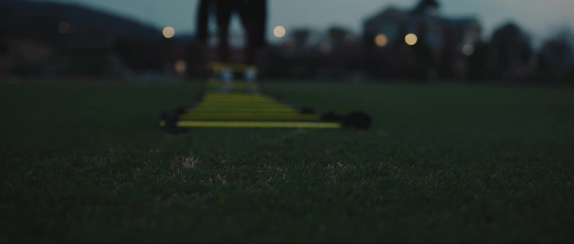 Male athlete sets up training equipment on the field after dusk