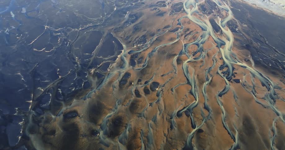 Aerial view of a complex network of winding river channels cutting through a brown landscape