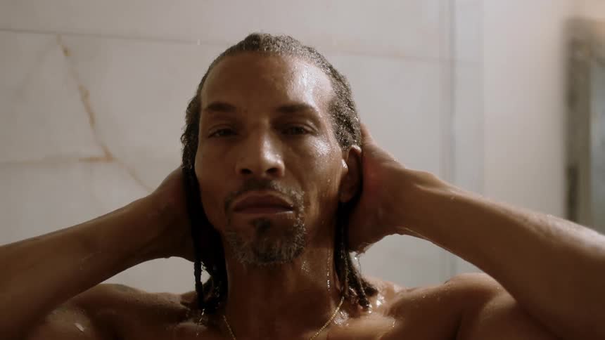 A person showering water flowing down their hair and body