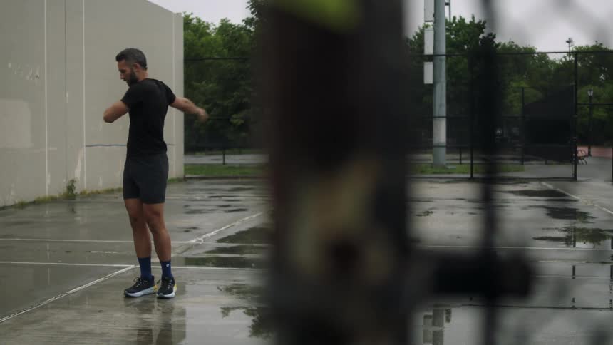 Man standing on wet asphalt stretching his arms