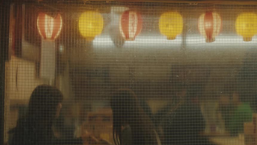 Outside view of people in an asian restaurant at night having dinner