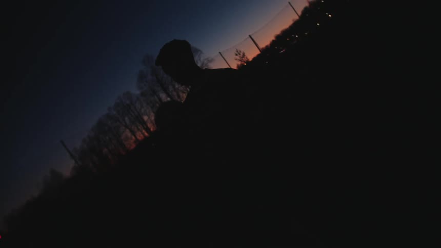 Silhouette of a boy doing freestyle with a ball outdoors at night
