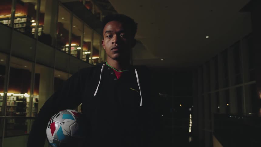 A man is holding a soccer ball in the library