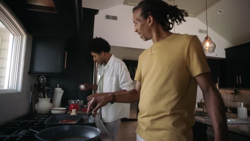 Two men talk as they cook in the kitchen