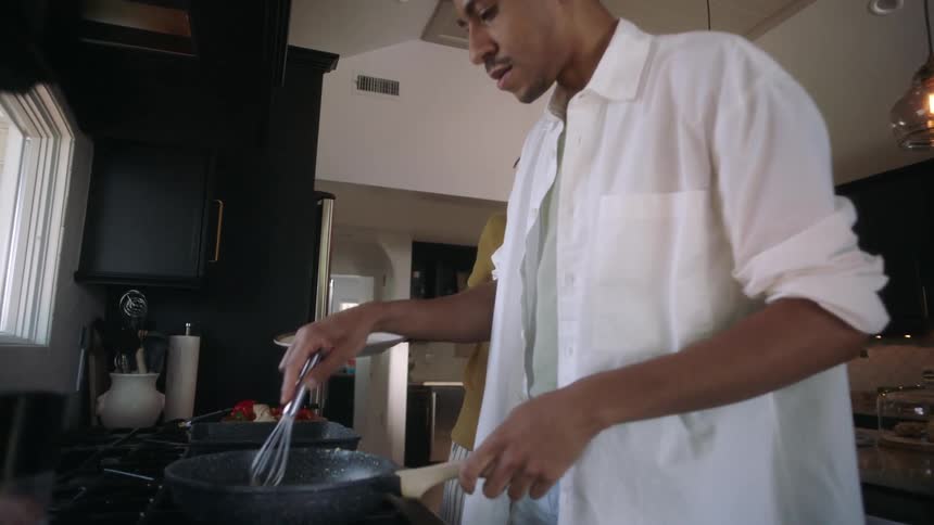 Two men are cooking and talking in the kitchen