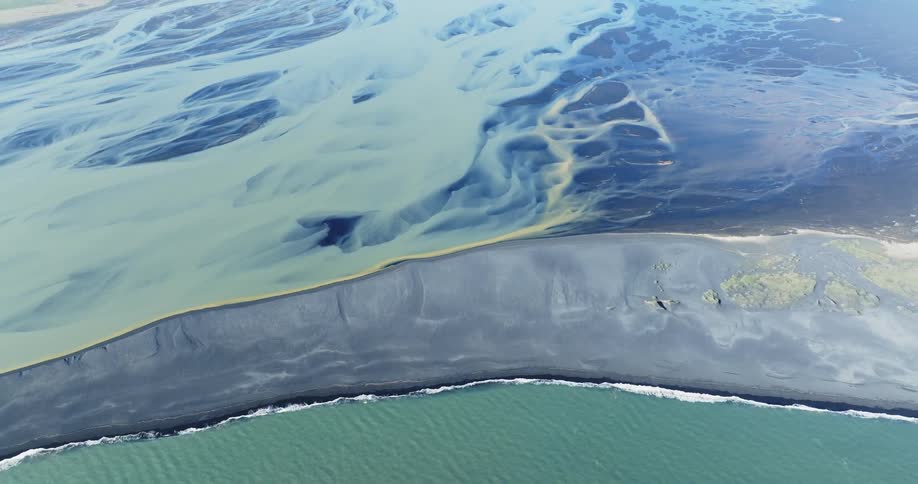 An aerial view of a coastline where the ocean meets a sandy beach
