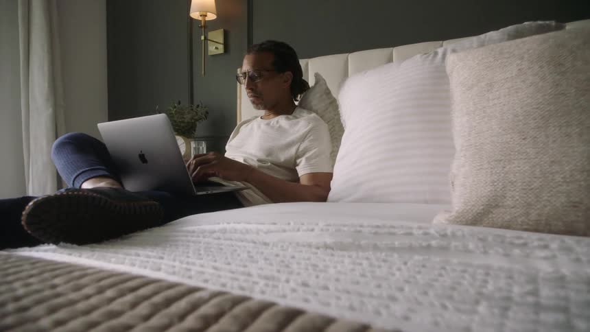 A man is using his laptop in bed