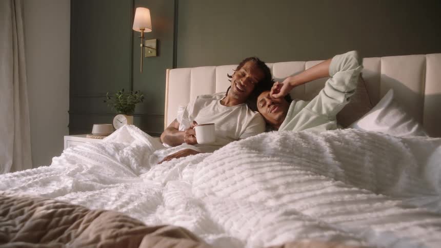 Two men talk in bed together