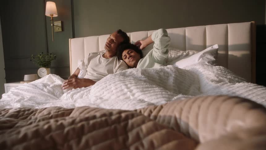 Two men lying hugging each other in bed