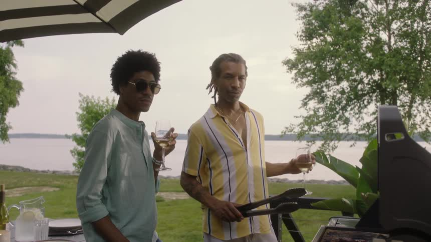 Two men stand still by the grill