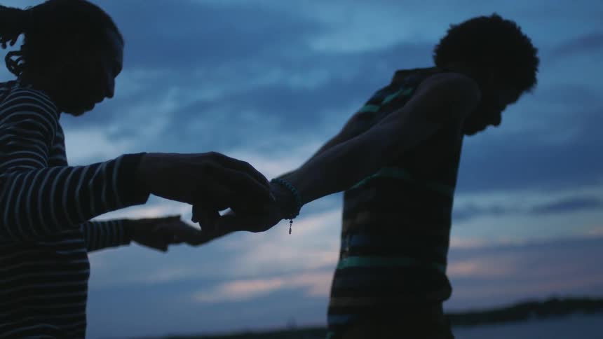 Silhouette of two men holding hands walking together in a natural environment