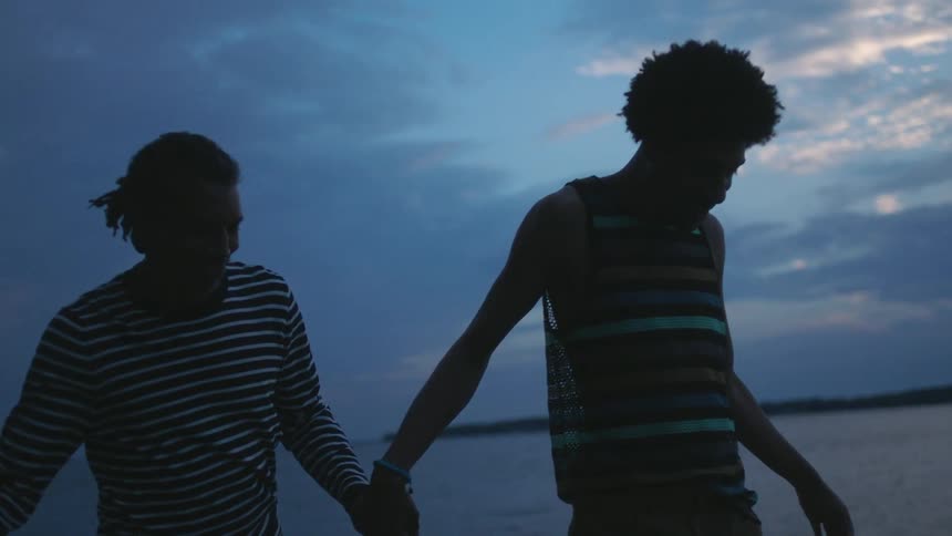 A couple holds hands while walking in the water