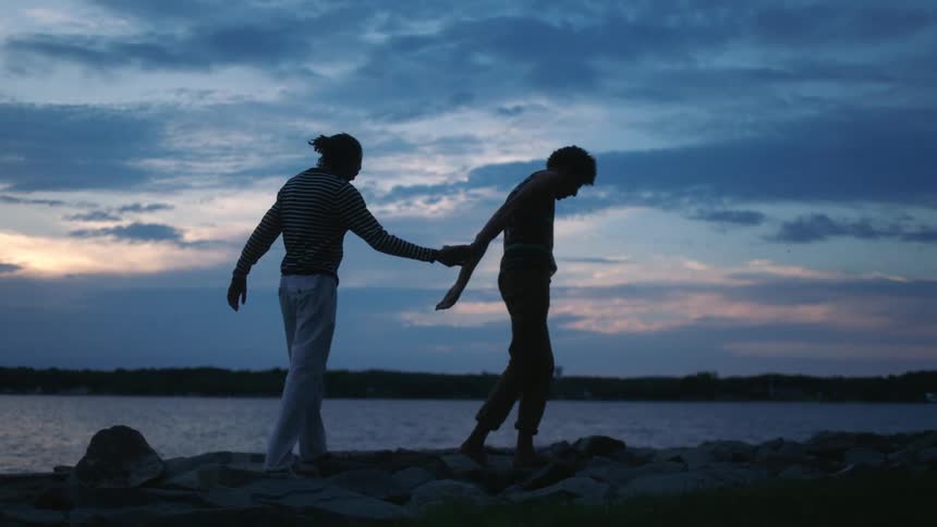 A couple hold hands while walking on the beach