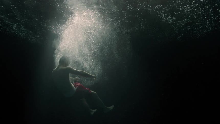 Body of a man in free fall submerged in the ocean