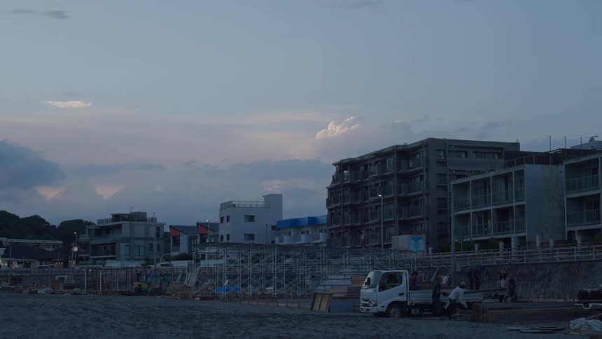 Urban city scene with vehicle traffic and workers removing equipment from a small truck in the sand