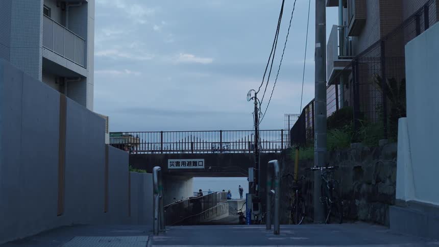 An urban alleyway dimly lit leads to an underpass flanked by buildings