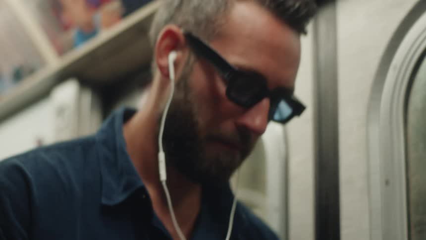 A man types a text message on a smartphone while on a subway train