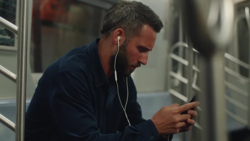 Man sitting using his cell phone inside a train